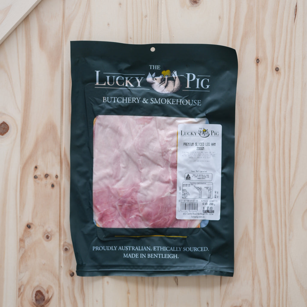 The Lucky Pig premium sliced leg ham in a 200 g retail pouch on a wooden board