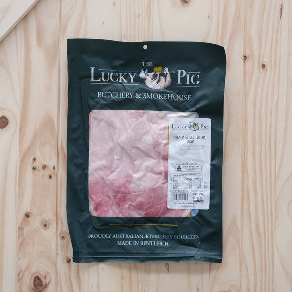 The Lucky Pig premium sliced leg ham in a 200 g retail pouch on a wooden board